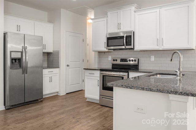 10410 Bradstreet Commons Way, Charlotte, NC 28215 - kitchen with appliances with stainless steel finishes, white cabinets, dark stone countertops, a peninsula, and backsplash