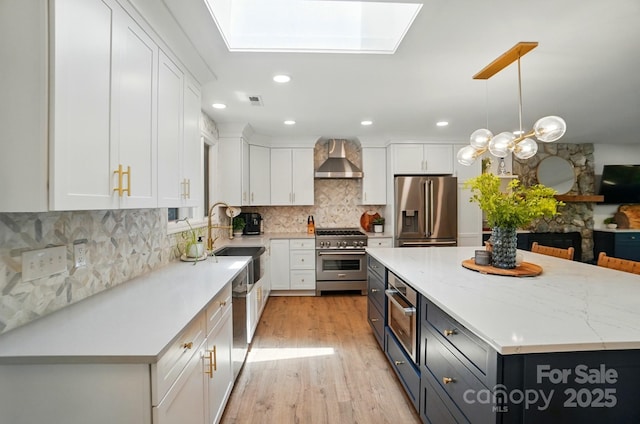 10043 Tepa Pl, Tega Cay, SC 29708 - kitchen with appliances with stainless steel finishes, wall chimney exhaust hood, white cabinetry, a sink, and recessed lighting