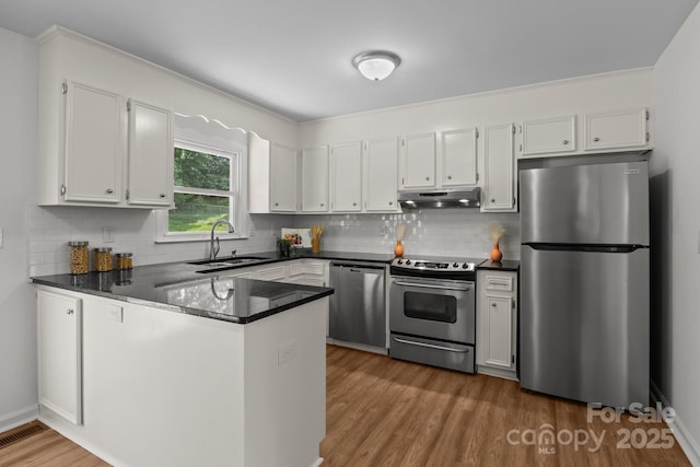 146 Duff St, Gastonia, NC 29715 - kitchen with appliances with stainless steel finishes, a sink, a peninsula, under cabinet range hood, and white cabinetry