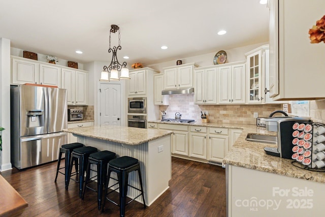 274 Cove Creek Loop, Mooresville, NC 28117 - kitchen with appliances with stainless steel finishes, a center island, dark wood-style floors, a kitchen breakfast bar, and light stone counters