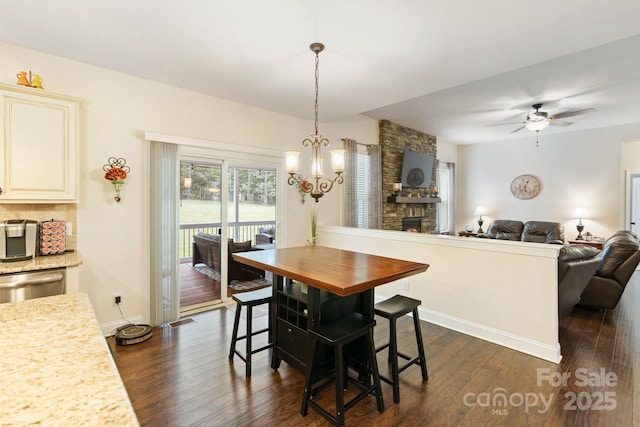 274 Cove Creek Loop, Mooresville, NC 28117 - dining room featuring dark wood-style flooring, a chandelier, a fireplace, and a ceiling fan