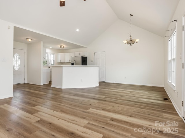 7006 Lone Eagle Dr # 18, Monroe, NC 28110 - unfurnished living room featuring a chandelier, high vaulted ceiling, ceiling fan, and light wood-type flooring