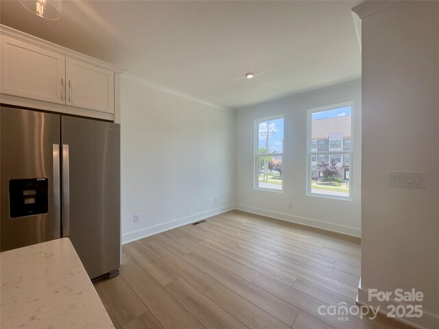 3618 S Tryon St Unit 19, Charlotte, NC 28217 - unfurnished dining area with light wood finished floors, baseboards, and crown molding