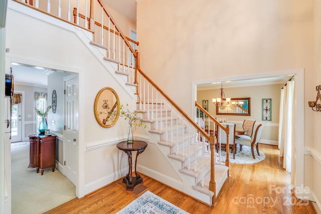 10127 Tallent Ln, Huntersville, NC 28078 - stairway featuring a chandelier, a high ceiling, wood finished floors, and ornamental molding
