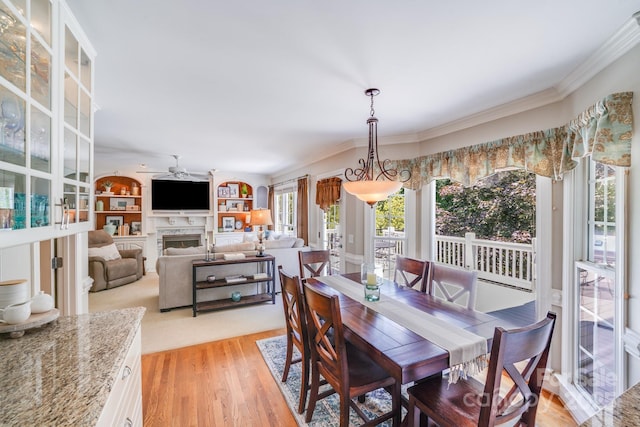 10127 Tallent Ln, Huntersville, NC 28078 - dining area featuring a ceiling fan, crown molding, a fireplace, and light wood-style flooring