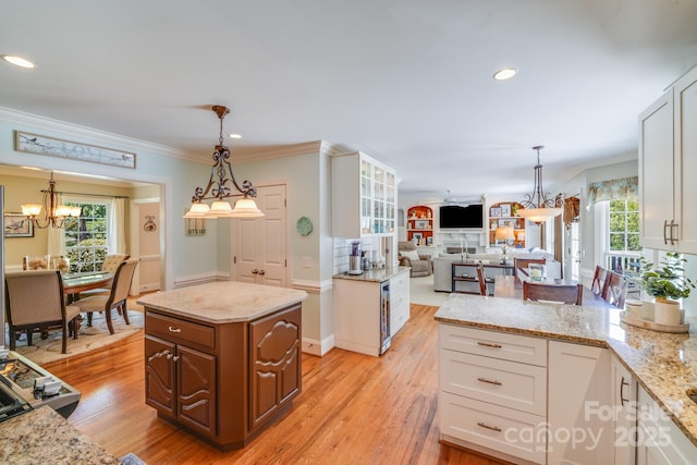 10127 Tallent Ln, Huntersville, NC 28078 - kitchen with a chandelier, crown molding, light stone countertops, open floor plan, and light wood-style flooring