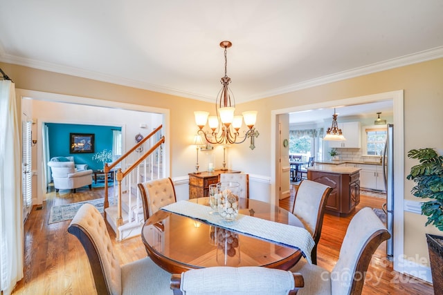 10127 Tallent Ln, Huntersville, NC 28078 - dining space with ornamental molding, light wood-type flooring, a chandelier, and stairway