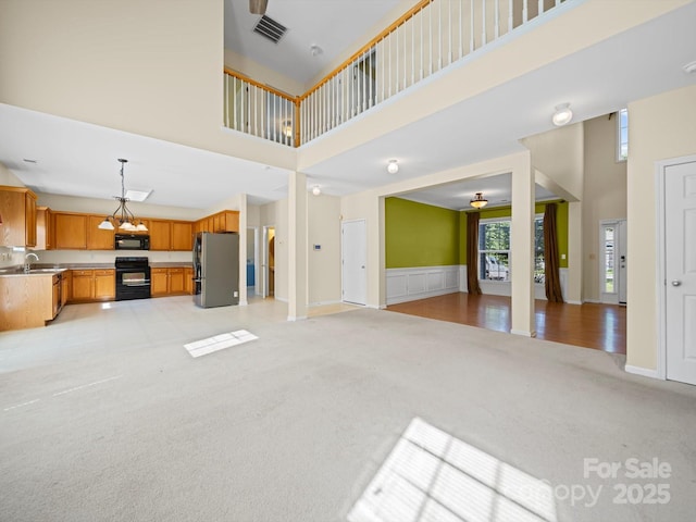 5921 Firethorne Ln, Concord, NC 28025 - unfurnished living room featuring a towering ceiling, light carpet, a wainscoted wall, and a ceiling fan