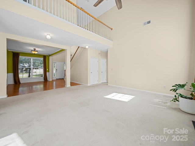 5921 Firethorne Ln, Concord, NC 28025 - unfurnished living room featuring carpet floors, a ceiling fan, a high ceiling, baseboards, and stairs