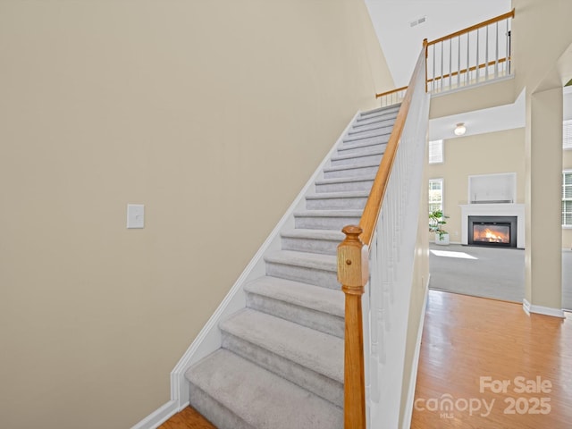 5921 Firethorne Ln, Concord, NC 28025 - stairway with wood finished floors, a high ceiling, baseboards, and a glass covered fireplace