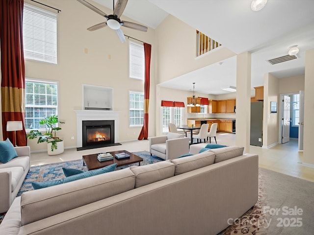 5921 Firethorne Ln, Concord, NC 28025 - living area featuring a towering ceiling, a ceiling fan, a glass covered fireplace, healthy amount of natural light, and baseboards