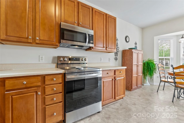 1418 Skidaway St NW Unit 427, Concord, NC 28027 - kitchen featuring stainless steel appliances, light countertops, brown cabinetry, and light tile patterned flooring