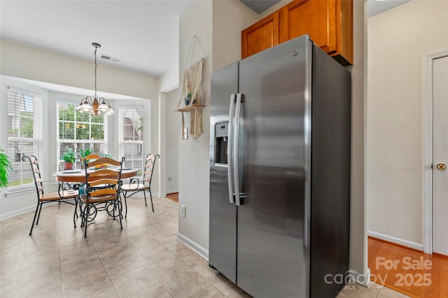 1418 Skidaway St NW Unit 427, Concord, NC 28027 - kitchen with stainless steel fridge, brown cabinets, light tile patterned floors, a chandelier, and decorative light fixtures