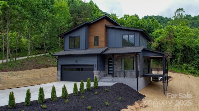 127 View Ridge Parkway, Leicester, NC 28748 - contemporary house with covered porch, an attached garage, driveway, a view of trees, and stone siding