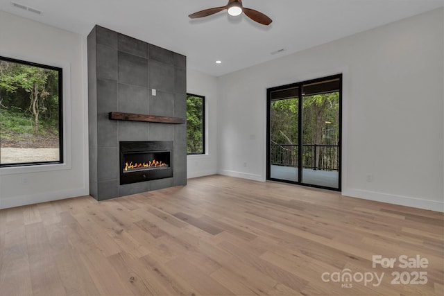 127 View Ridge Parkway, Leicester, NC 28748 - unfurnished living room with light wood-type flooring, a ceiling fan, a tiled fireplace, and healthy amount of natural light