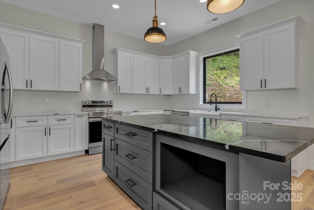 127 View Ridge Parkway, Leicester, NC 28748 - kitchen featuring appliances with stainless steel finishes, wall chimney exhaust hood, white cabinetry, decorative light fixtures, and light wood-style floors