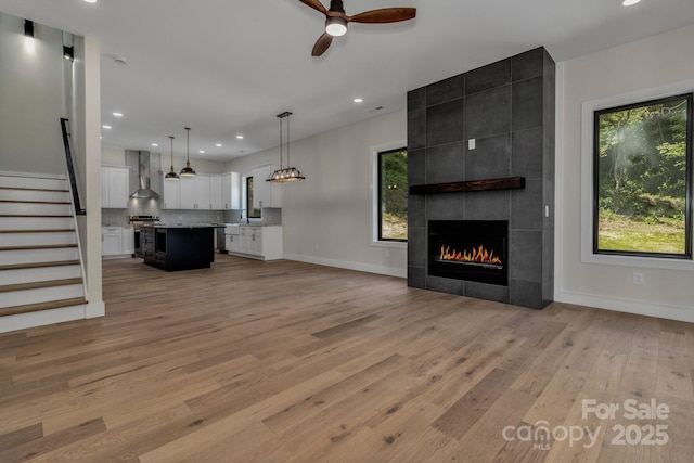127 View Ridge Parkway, Leicester, NC 28748 - unfurnished living room featuring light wood-style flooring, a tile fireplace, a ceiling fan, recessed lighting, and stairs