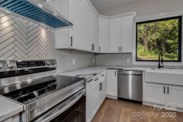 127 View Ridge Parkway, Leicester, NC 28748 - kitchen with appliances with stainless steel finishes, wall chimney range hood, decorative backsplash, white cabinetry, and wood finished floors