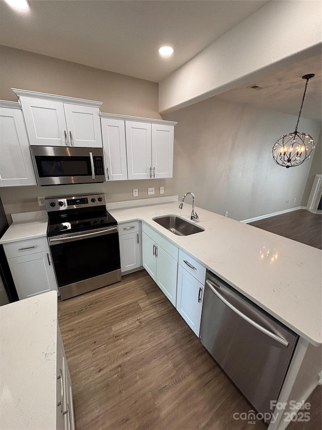 4151 Town Center Rd, Harrisburg, NC 28075 - kitchen featuring a sink, appliances with stainless steel finishes, white cabinetry, dark wood-type flooring, and a peninsula