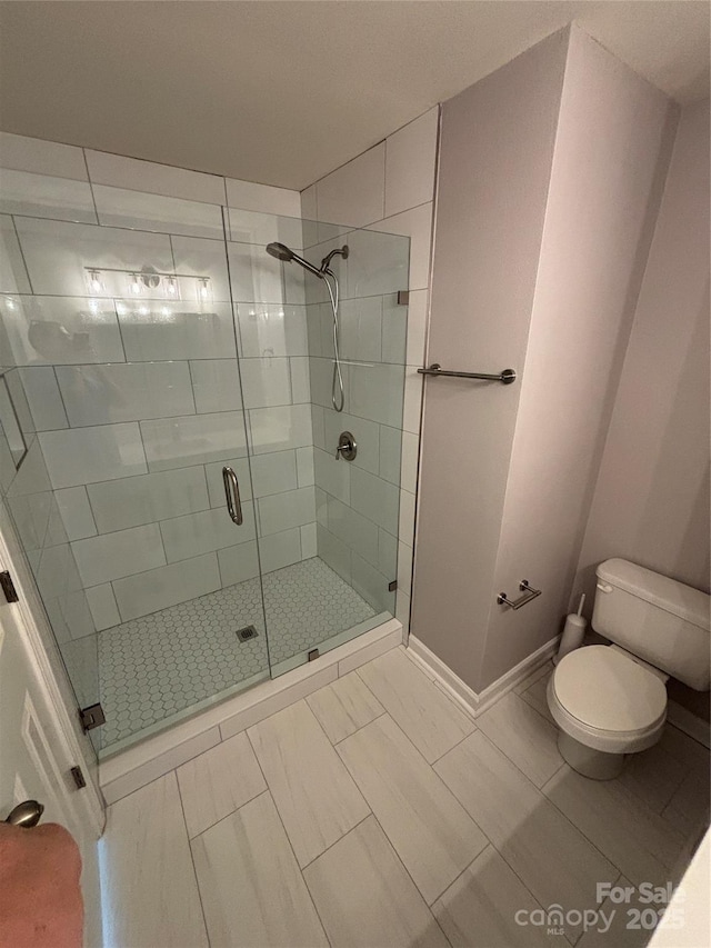 4151 Town Center Rd, Harrisburg, NC 28075 - bathroom featuring toilet, a stall shower, marble look tiles, and baseboards