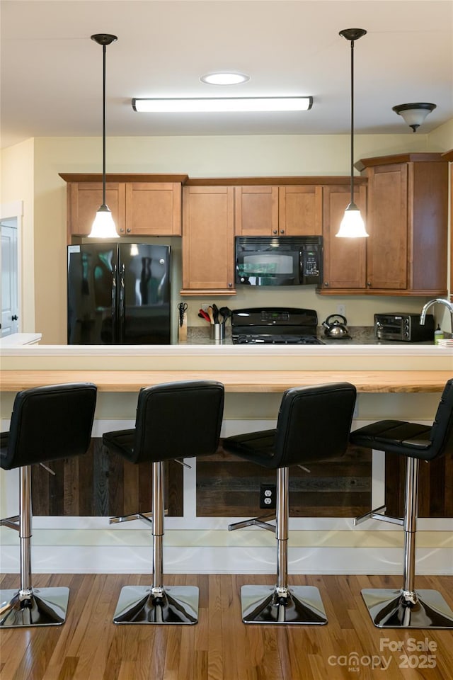 26 Byrdcliffe Ln, Asheville, NC 28805 - kitchen with black appliances, brown cabinetry, a kitchen bar, and pendant lighting