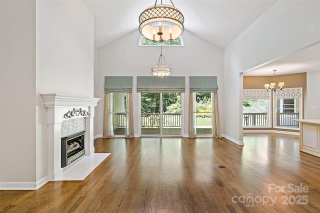 57 Rocky Branch Trl, Marion, NC 28752 - unfurnished living room featuring a chandelier, high vaulted ceiling, a tiled fireplace, and wood finished floors