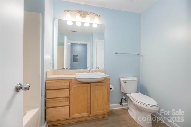 411 W Washington St, Greensboro, NC 27401 - full bathroom featuring wood finished floors, toilet, vanity, baseboards, and a tub