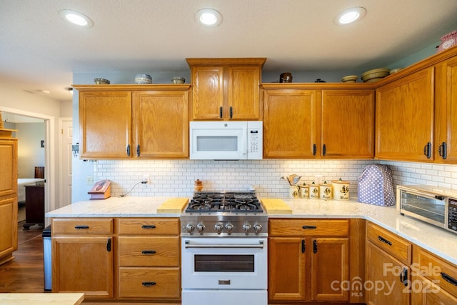 347 Hickory Mountain Rd, Sparta, NC 28675 - kitchen with white microwave, gas stove, backsplash, light stone counters, and recessed lighting
