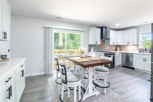 2116 Eastway Dr, Charlotte, NC 28205 - kitchen with dishwasher, range with electric cooktop, wall chimney range hood, decorative backsplash, and light wood-style floors