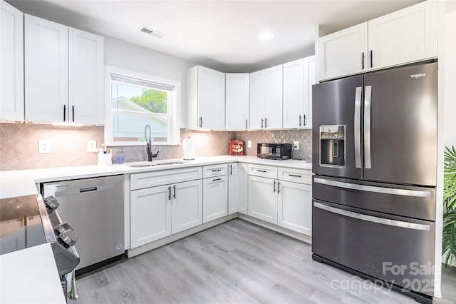 2116 Eastway Dr, Charlotte, NC 28205 - kitchen with stainless steel appliances, a sink, white cabinetry, light wood-style flooring, and light countertops