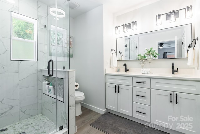 2116 Eastway Dr, Charlotte, NC 28205 - full bathroom featuring toilet, double vanity, a marble finish shower, wood finished floors, and a ceiling fan