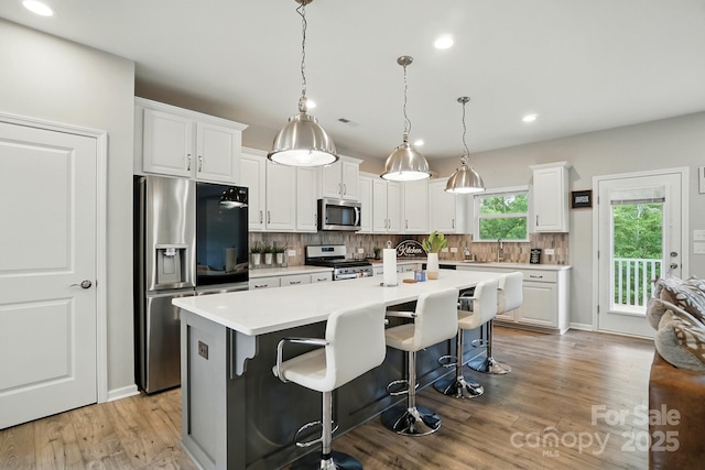 18619 Mainsail Ct, Lancaster, SC 29720 - kitchen featuring stainless steel appliances, a breakfast bar area, backsplash, white cabinets, and light wood-type flooring