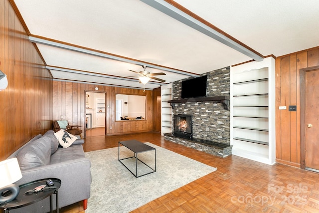 1107 Fairfield Dr, Gastonia, NC 28054 - living room with wood walls, a fireplace, a ceiling fan, beam ceiling, and built in shelves