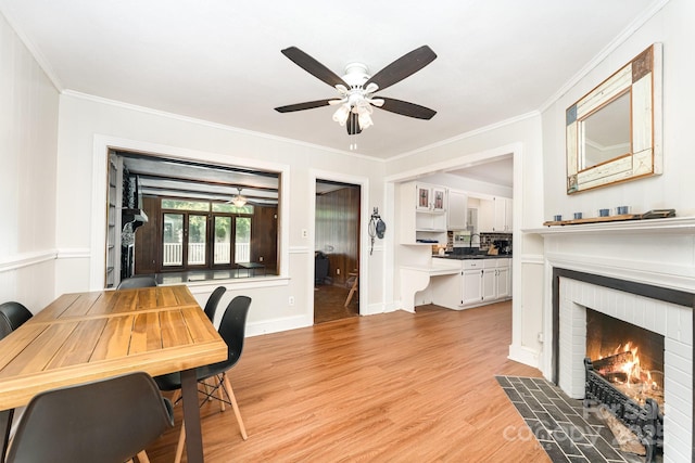 1107 Fairfield Dr, Gastonia, NC 28054 - dining room featuring a ceiling fan, light wood-type flooring, crown molding, a brick fireplace, and baseboards