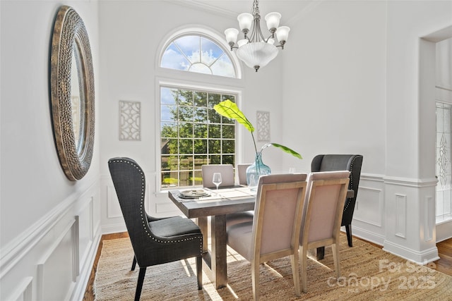 3831 Riceland Pl, Charlotte, NC 28216 - dining area with a decorative wall, a chandelier, wainscoting, light wood finished floors, and crown molding