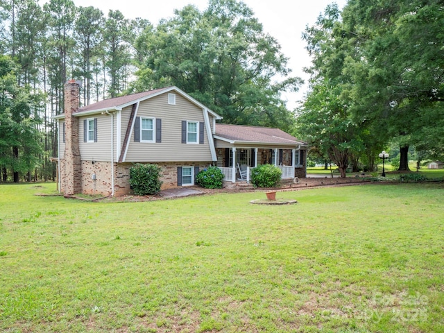 409 Ridge Rd, Clover, SC 29710 - split level home featuring a porch, a chimney, a front yard, brick siding, and view of wooded area