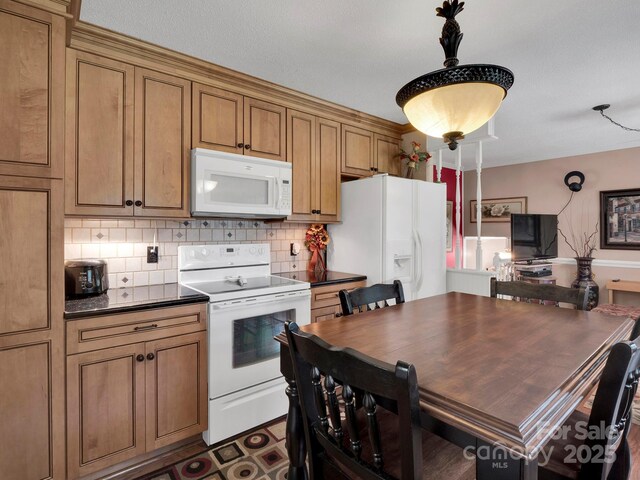 409 Ridge Rd, Clover, SC 29710 - kitchen with white appliances, dark countertops, brown cabinets, backsplash, and pendant lighting
