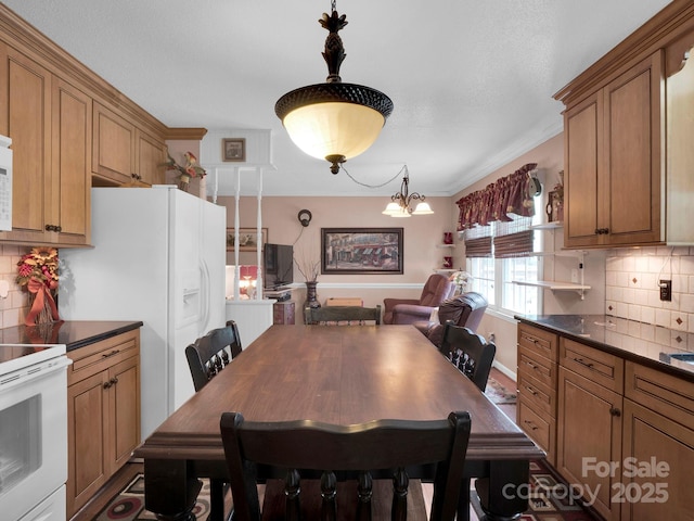 409 Ridge Rd, Clover, SC 29710 - kitchen featuring white appliances, dark countertops, brown cabinets, tasteful backsplash, and hanging light fixtures