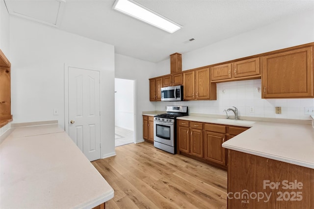 13832 Queenswater Ln, Charlotte, NC 28273 - kitchen featuring stainless steel appliances, a sink, brown cabinetry, tasteful backsplash, and light countertops