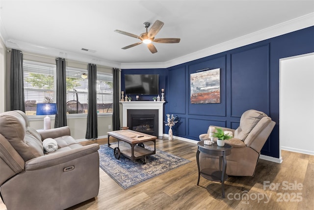 5059 Fenwick Ct, Lancaster, SC 29720 - living area featuring ceiling fan, crown molding, wood finished floors, a glass covered fireplace, and a decorative wall