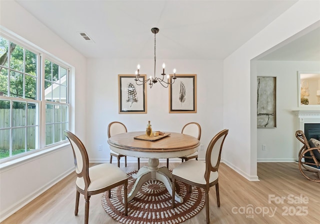 5229 Tarrywood Ln, Charlotte, NC 28205 - dining area with light wood-style floors, a chandelier, baseboards, and a fireplace