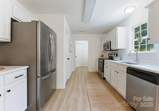 5229 Tarrywood Ln, Charlotte, NC 28205 - kitchen featuring stainless steel appliances, a sink, light wood-style flooring, and white cabinetry