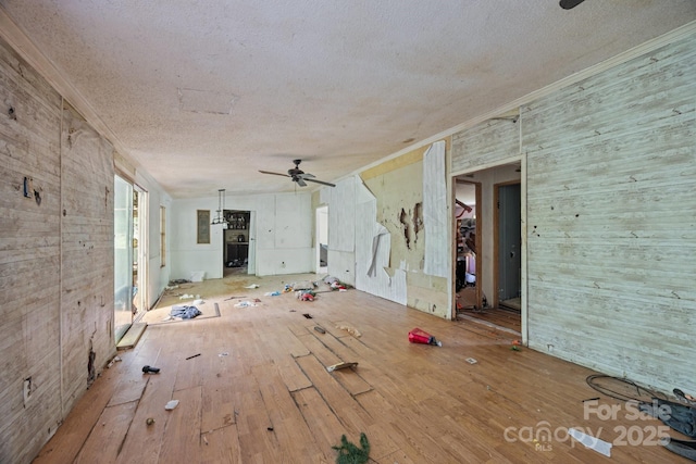 99 Bridges Cove Rd, Leicester, NC 28748 - unfurnished living room featuring wood walls, a textured ceiling, wood-type flooring, ceiling fan, and crown molding