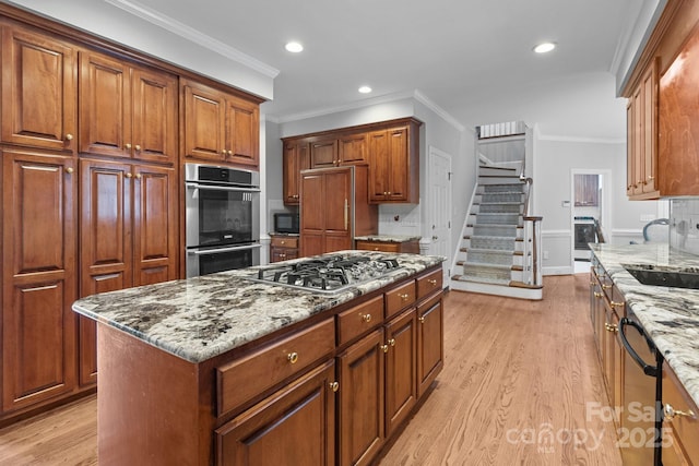 654 9th St N, Albemarle, NC 28001 - kitchen featuring appliances with stainless steel finishes, light stone counters, crown molding, light wood-style flooring, and a sink