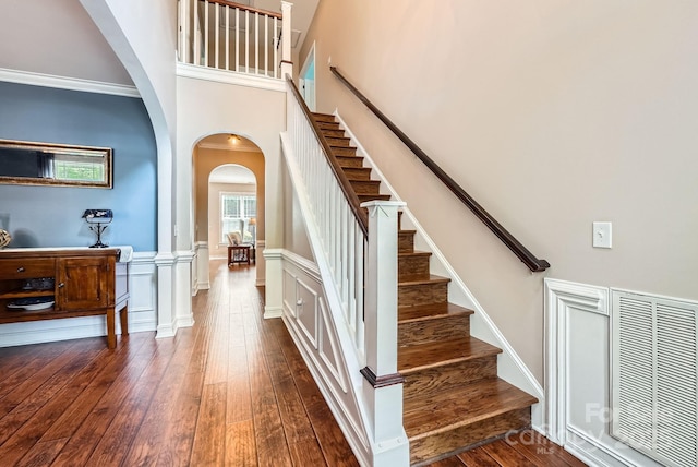 18732 Coachmans Trce, Cornelius, NC 28031 - staircase featuring arched walkways, hardwood / wood-style flooring, a wainscoted wall, and a high ceiling