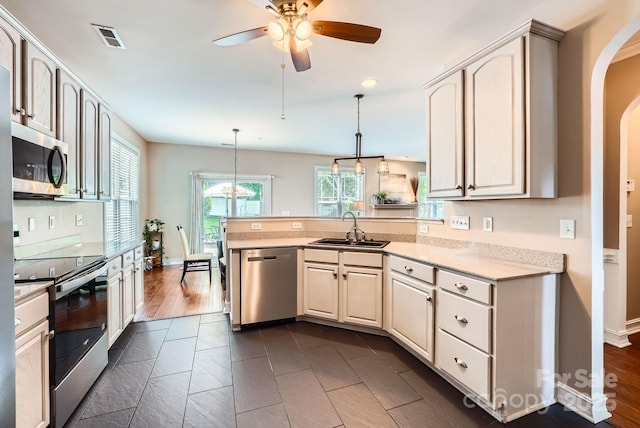 18732 Coachmans Trce, Cornelius, NC 28031 - kitchen with appliances with stainless steel finishes, a peninsula, ceiling fan, arched walkways, and pendant lighting