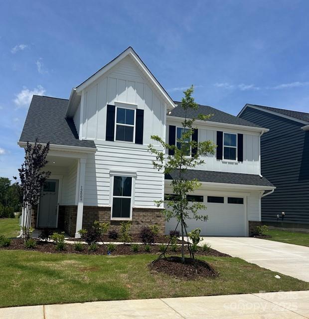 12009 Grinstead Ln Unit 303, Charlotte, NC 28278 - view of front of house with board and batten siding, driveway, a garage, and a front yard