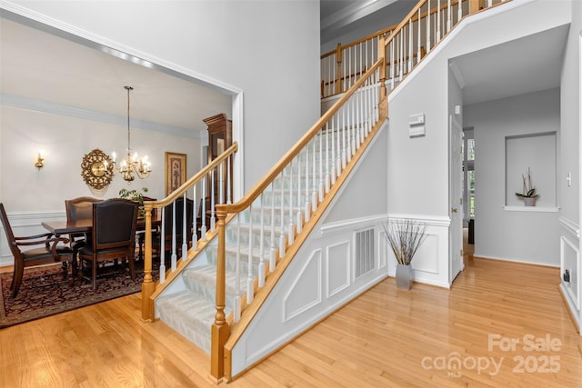 3213 Strawberry Rd, Matthews, NC 28104 - stairway featuring wood finished floors, a chandelier, crown molding, and a high ceiling