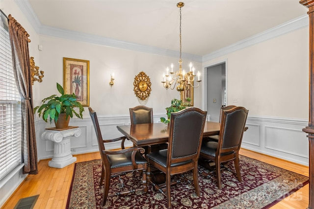 3213 Strawberry Rd, Matthews, NC 28104 - dining room featuring a chandelier, crown molding, wainscoting, light wood-type flooring, and a decorative wall