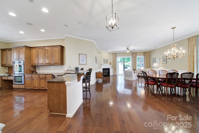 964 Knob Creek Ln, Fort Mill, SC 29708 - kitchen with a chandelier, stainless steel double oven, brown cabinets, a kitchen bar, and ornamental molding